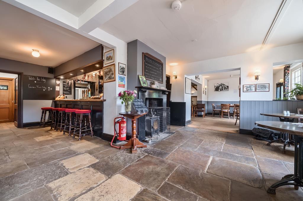 Lot: 147 - FREEHOLD PUBLIC HOUSE WITH LIVING ACCOMMODATION ABOVE - Flagstone flooring with stools and bar serving area